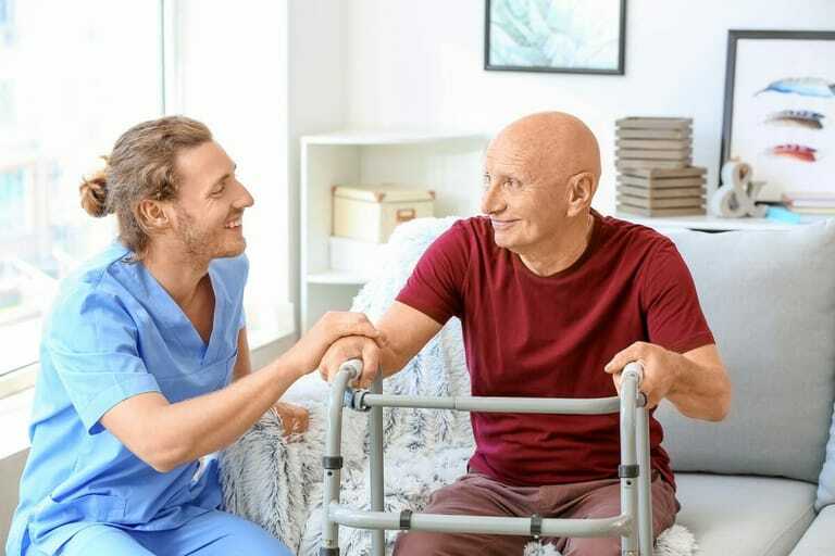 Ein Pfleger umsorgt einen älteren Patienten.